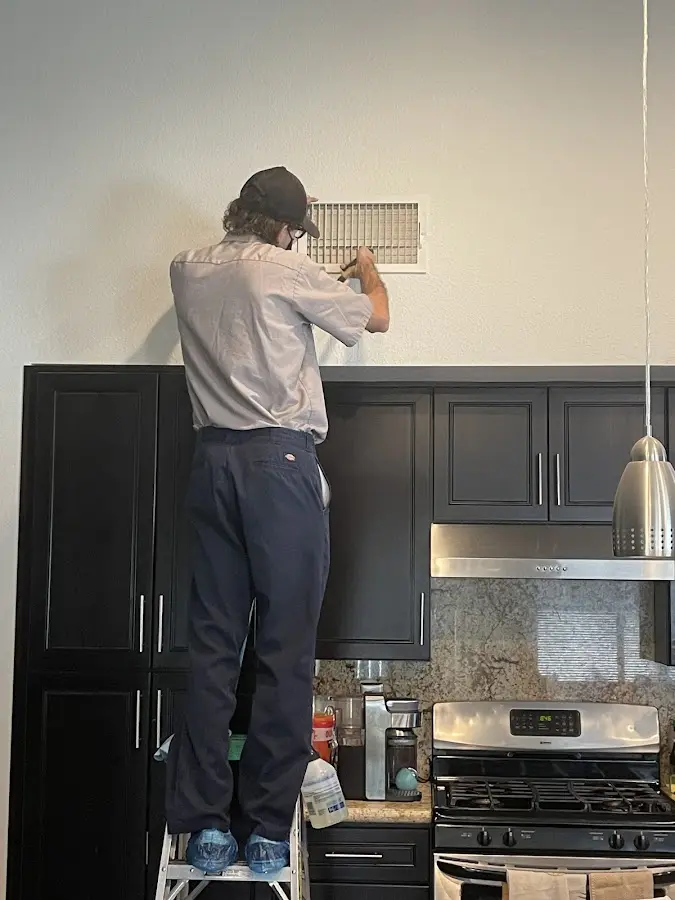 Technician inspecting an air vent during HVAC service in Bangor Base